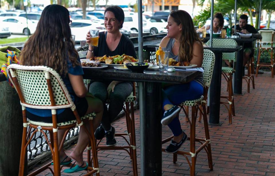 From left to right: Natalie Abad, 26, Monique Motta, 26, and Valeria Mantilla, 25, eat at Flanigan's in Kendall on the first day Miami-Dade County allowed restaurants to reopen their dining rooms on Monday, May 18, 2020. 