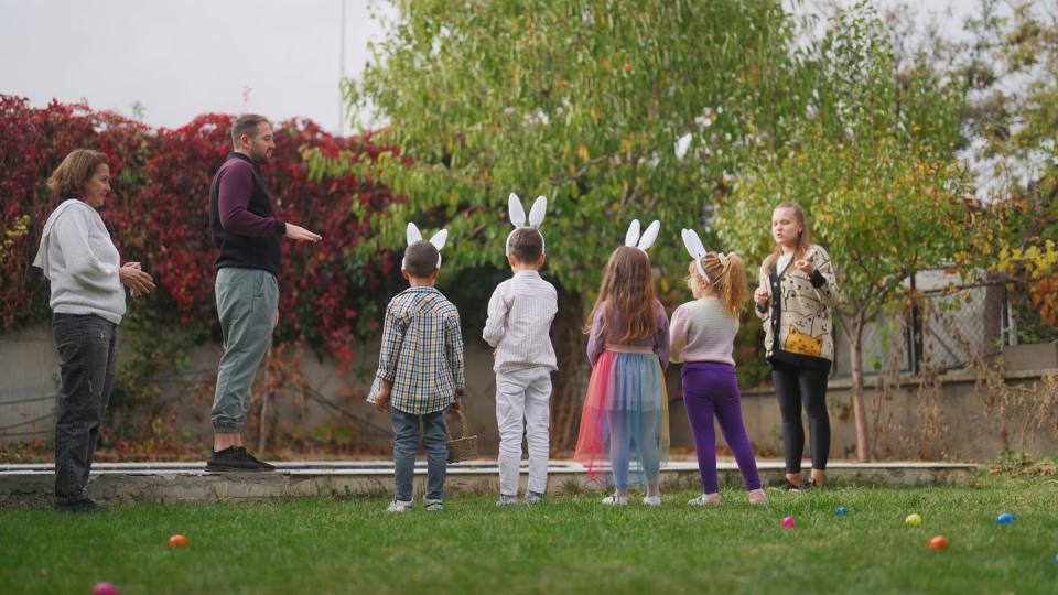 group of excited children running around in garden on easter egg hunt game