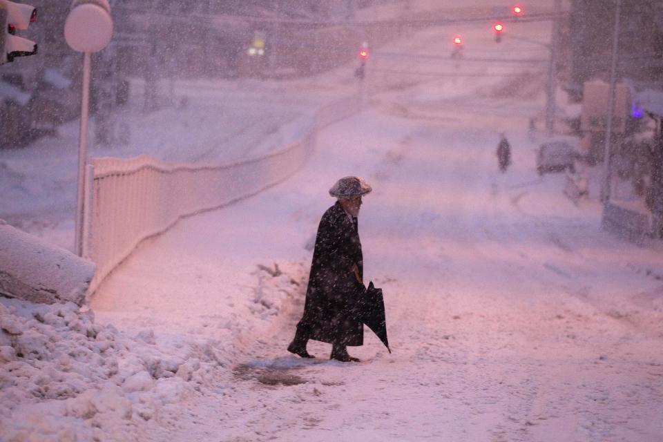 An ultra-Orthodox Jewish man walks on a snow-covered street early morning near Jerusalem's Mea Shearim neighbourhood