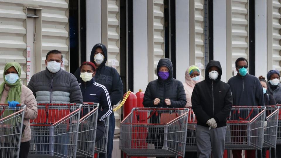 Una fila de compradores todos con mascarillas