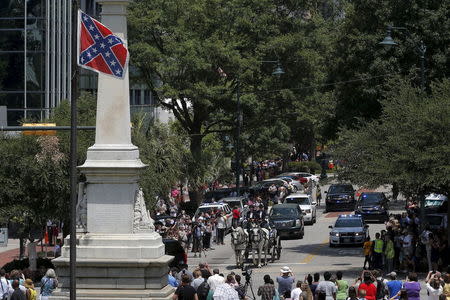 A horse drawn carriage carries the casket of the late South Carolina State Senator Clementa Pinckney past the Confederate flag and onto the grounds of the South Carolina State Capitol in Columbia, South Carolina, June 24, 2015. REUTERS/Brian Snyder