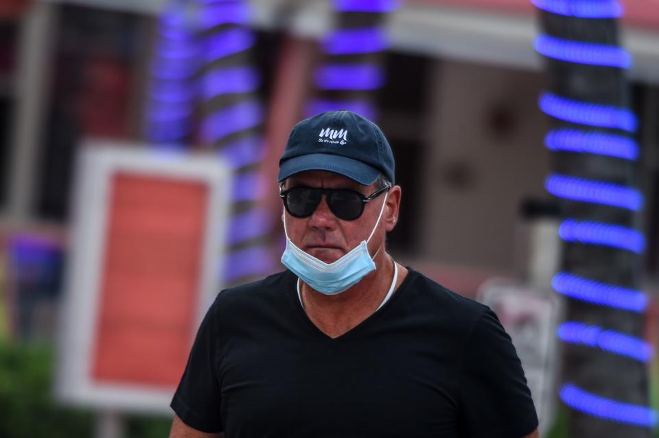 A man wears a facemask on his chin on Ocean Drive in South Beach, Miami, on May 19, 2020, amid the novel coronavirus pandemic. (Photo by CHANDAN KHANNA / AFP) (Photo by CHANDAN KHANNA/AFP via Getty Images)