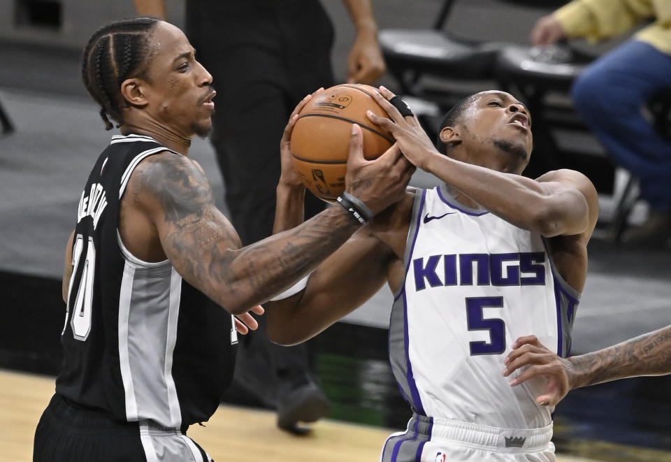 San Antonio Spurs' DeMar DeRozan, left, strips the ball from Sacramento Kings' De'Aaron Fox during the second half of an NBA basketball game Wednesday, March 31, 2021, in San Antonio. (AP Photo/Darren Abate)