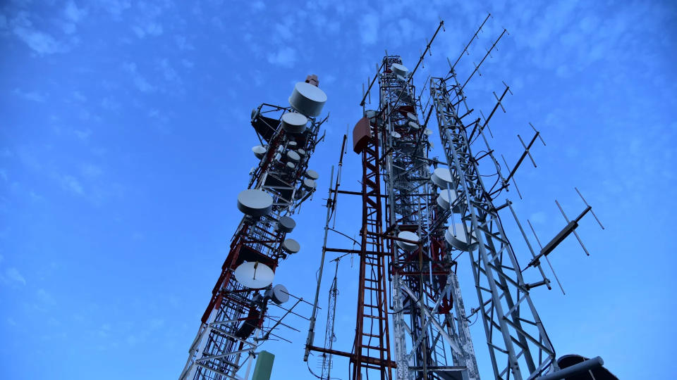 Some phone network towers in front of a blue sky