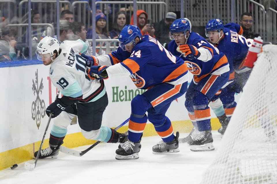 New York Islanders' Scott Mayfield, second from left, shoves Seattle Kraken's Jared McCann (19), left, during the first period of an NHL hockey game, Tuesday, Feb. 13, 2024, in Elmont, N.Y. (AP Photo/Seth Wenig)
