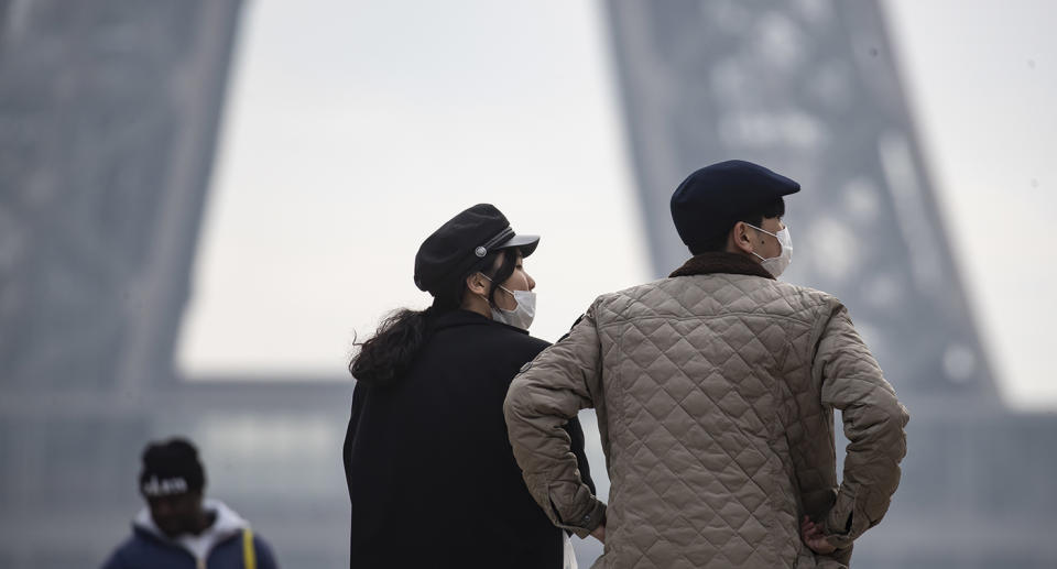 Tourists wear face masks near the Eiffel Tower in Paris