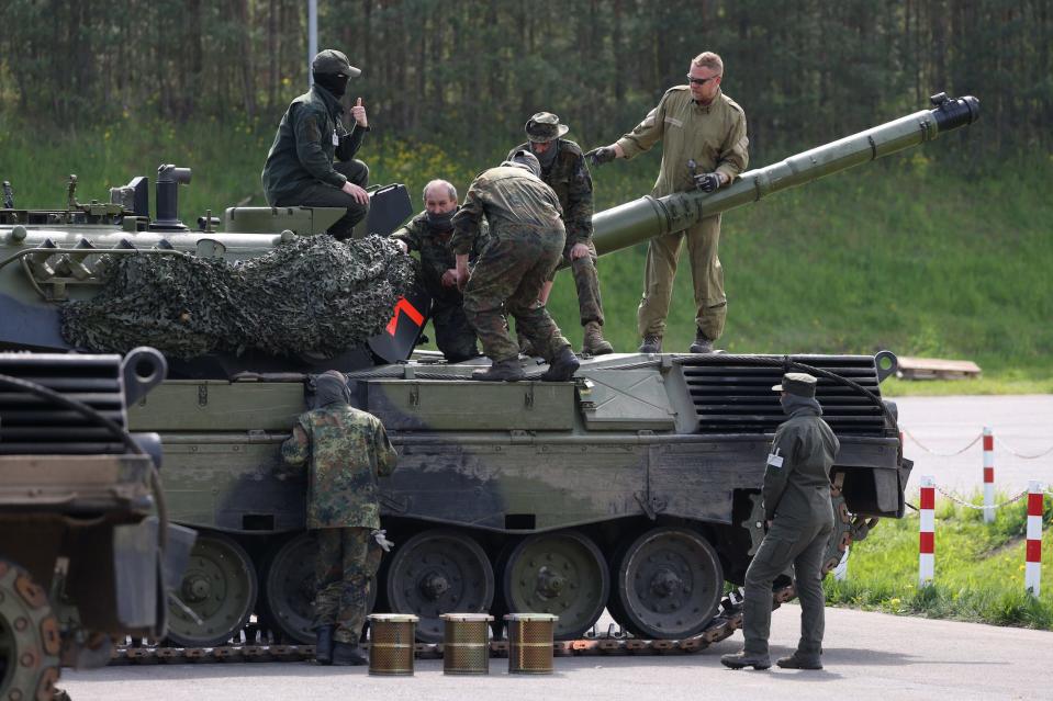 Tank crew standing on and inspecting a tank.