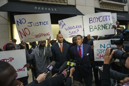 Reverend Conrad Tillard speaks in front of a Barneys luxury department store while standing with demonstrators holding signs decrying allegations that Barney's and Macy's stores have unfair security policies aimed at minorities in New York October 30, 2013. REUTERS/Lucas Jackson