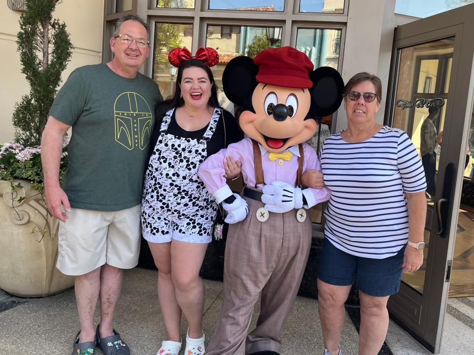 megan and her parents posing with mickey mouse at Disneyland