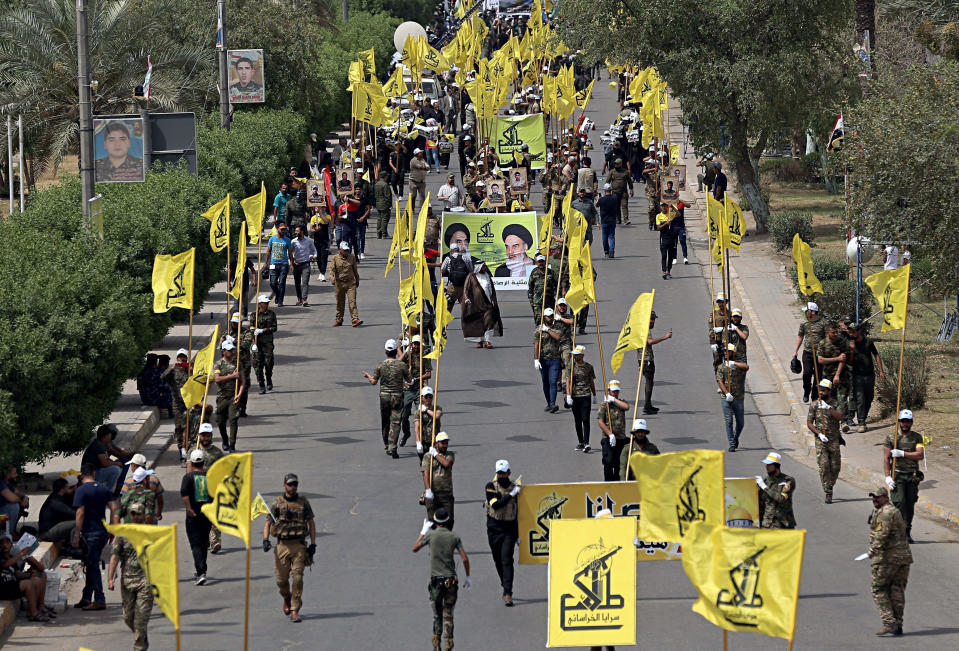 FILE - Iraqi Popular Mobilization Forces march as they hold their flag and posters of Iraqi and Iranian Shiite spiritual leaders during "al-Quds" or Jerusalem Day, in Baghdad, Iraq, June 8, 2018. Russia's invasion of Ukraine has brought up deep divisions in the Middle East While American influence has waned, Russia has made powerful friends, from Shiite militias in Iraq, to Lebanon’s Hezbollah group, to Houthi rebels in Yemen. These non-state actors want their countries to come out firmly in support of Russia. (AP Photo/Hadi Mizban, File)