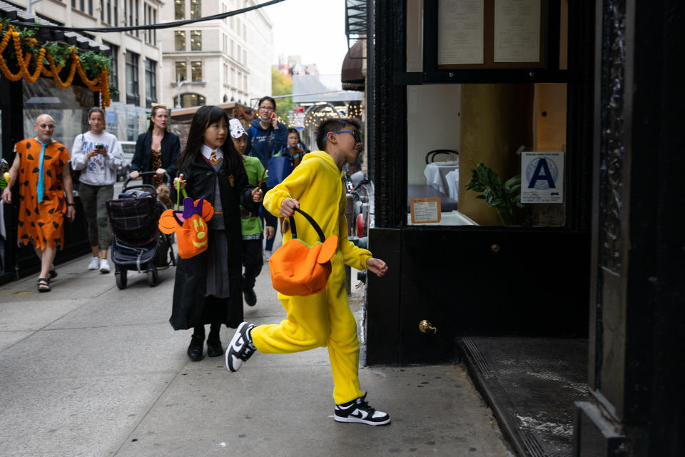 A child wearing a costume runs into a business while trick-or-treating on Halloween in New York City in 2022.