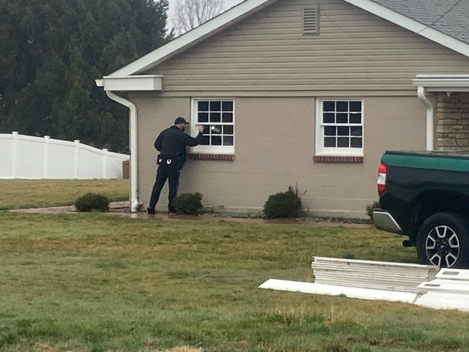 A Middletown police officer peers into a garage window at the Langhorne-Yardley Road home of Curtis G. Smith on Tuesday March 5, 2024.