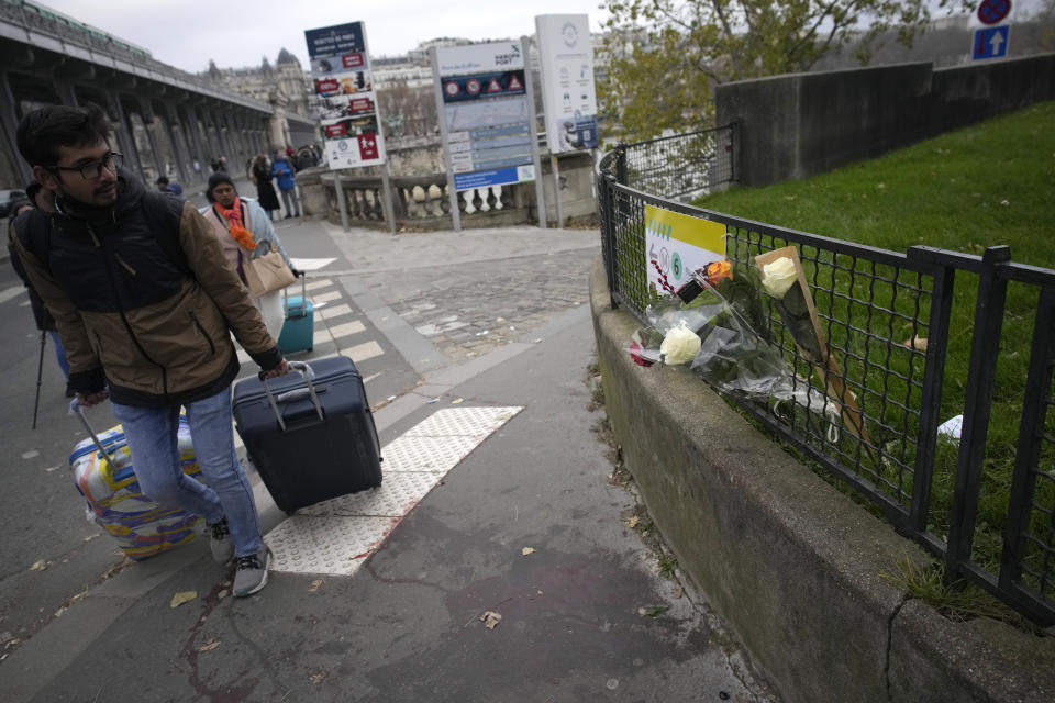 A man walks past flowers placed on the scene where a man targeted passersbys late saturday, killing a German tourist with a knife and injuring two others in Paris, Sunday, Dec. 3, 2023. Police subdued the man, a 25-year-old French citizen who had spent four years in prison for a violent offense. After his arrest, he expressed anguish about Muslims dying, notably in the Palestinian territories. (AP Photo/Christophe Ena)