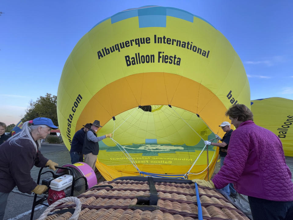 Crew members inflate a hot air balloon as part of a re-enactment of the first Albuquerque International Balloon Fiesta in 1972 during a special event at Coronado Center in Albuquerque, New Mexico, on Friday, Sept. 30, 2022. Hundreds of hot air balloons will be lifting off over the nine-day annual fiesta that has drawn pilots and spectators from across the globe for 50 years. (AP Photo/Susan Montoya Bryan)