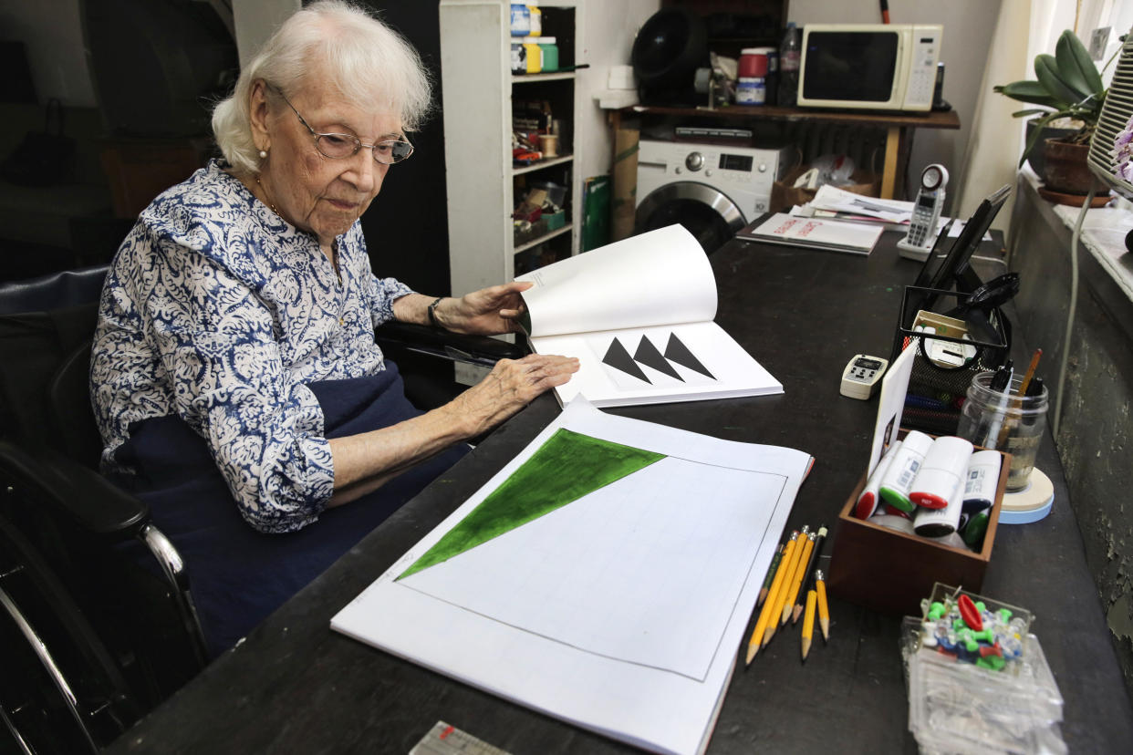 Carmen Herrera looks at a sketch for one of her paintings as she leafs through a gallery catalogue of some of her work in her New York studio on May 29, 2015. (Richard Drew / AP file)
