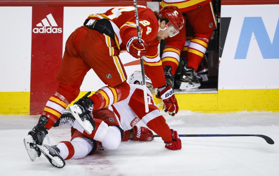 Detroit Red Wings forward Dylan Larkin, bottom, is knocked to the ice by Calgary Flames forward Brett Ritchie during first-period NHL hockey game action in Calgary, Alberta, Thursday, Feb. 16, 2023. (Jeff McIntosh/The Canadian Press via AP)