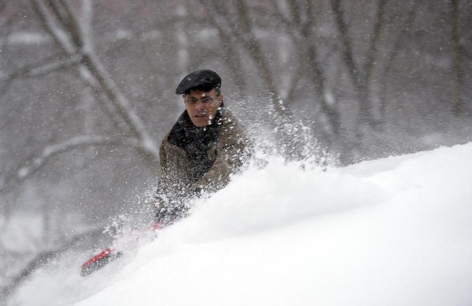 A man clears snow from a vehicle during a snow storm in Toronto