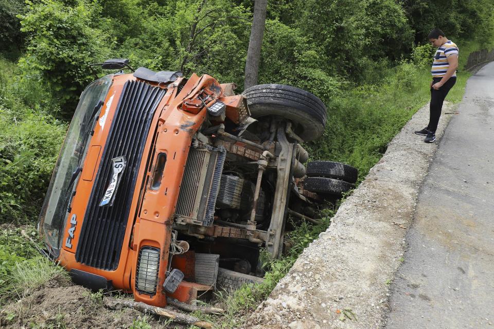 A man looks at a truck used as barricade and cleared by Kosovo police as it lies off the road near Zubin Potok, northern Kosovo, Tuesday, May 28, 2019. Serbia put its troops on full alert Tuesday after heavily armed Kosovo police entered Serb-dominated northern Kosovo, firing tear gas and arresting nearly two dozen people. (AP Photo/Bojan Slavkovic)