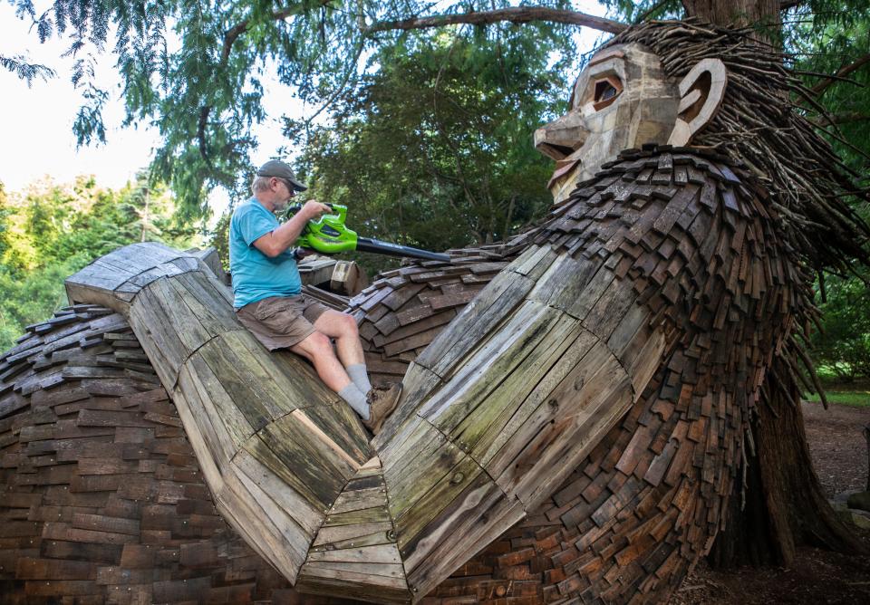 Volunteer and naturalist Doug Wilson blew debris off giant troll Mama Loumari at Bernheim Forest as part of an annual cleaning and repair of the wooden sculptures. July 20, 2022