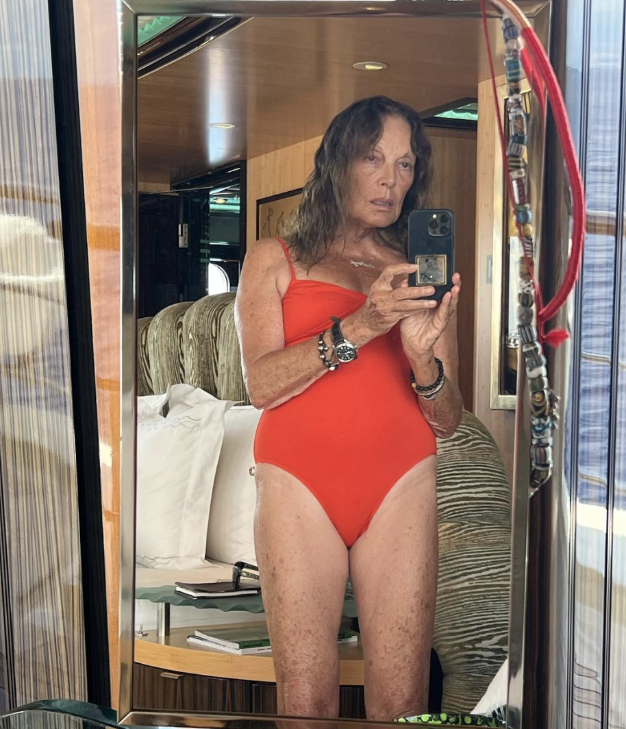 Diane von Furstenberg poses in front of a mirror in a red swimsuit. 