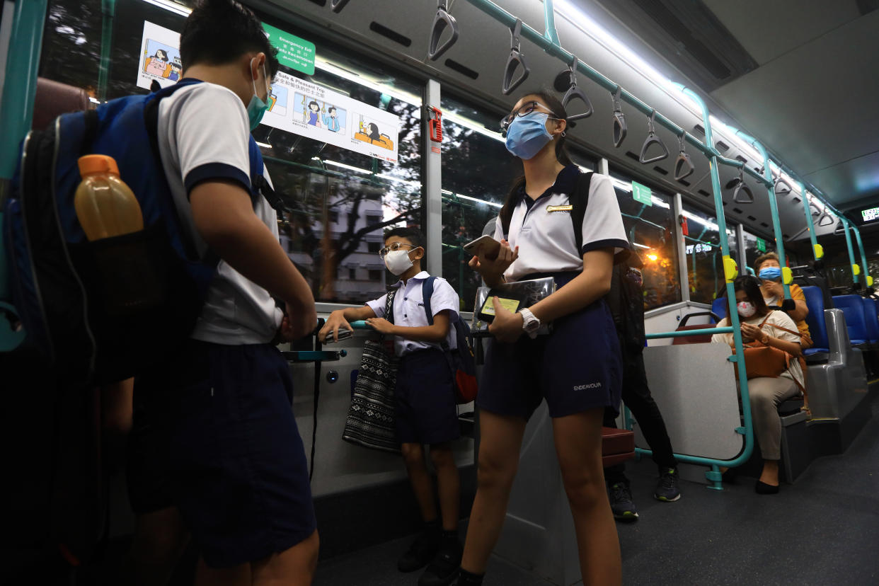 SINGAPORE - JUNE 08:  Students wearing protective masks commute to school by bus on June 8, 2020 in Singapore. The authority decided to remove all safe distancing stickers and markers from trains and buses as they deemed it is too challenging for commuters to keep their social distance. From June 2, Singapore embarked on phase one of a three phase approach against the coronavirus (COVID-19) pandemic as it began to ease the partial lockdown measures by allowing the safe re-opening of economic activities which do not pose high risk of transmission. This include the resumption of selected health services, re-opening of schools with school children attending schools on rotational basis, manufacturing and production facilities, construction sites that adhere to safety measures, finance and information services that do not require interactions and places of worship, amongst others. Retail outlets, social and entertainment activities will remain closed and dining in at food and beverage outlets will still be disallowed. The government will further ease restriction by the middle of June if the infection rate within the community remains low over the next two weeks.  (Photo by Suhaimi Abdullah/Getty Images)