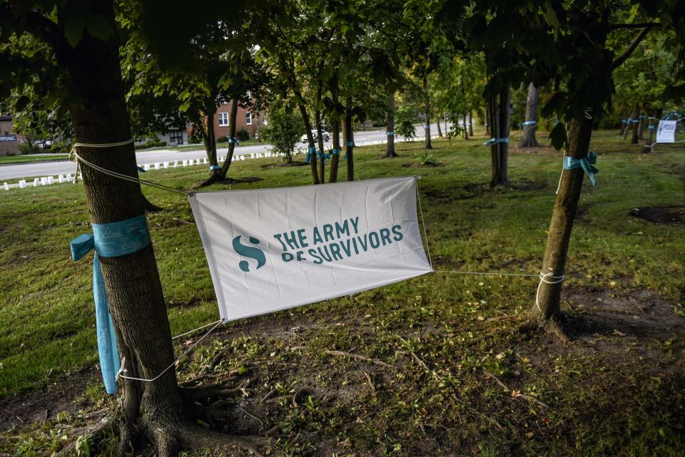 A banner representing The Army of Sister Survivors hangs in the trees on Thursday, Oct. 10, 2019, outside the East Lansing Library. Michigan State University Parents of Sister Survivors (POSSE) and The Army of Sister Survivors lit more than 505 luminarias as a reminder of the effects of sexual abuse prior to President Samuel Stanley's meeting with Larry Nassar survivors inside the library.