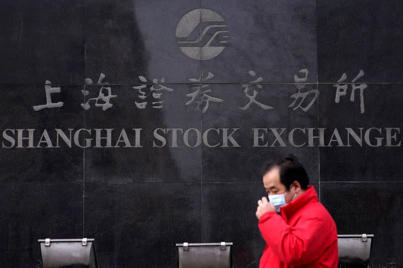 FILE PHOTO: A men wearing a mask walk at the Shanghai Stock Exchange building at the Pudong financial district in Shanghai