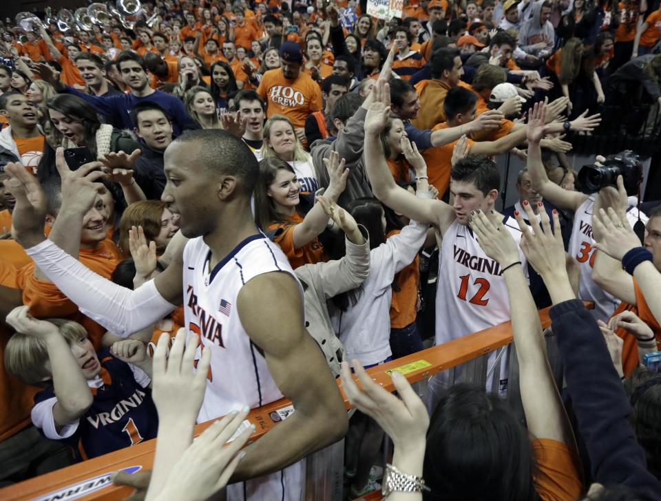 Virginia forward Akil Mitchell, front, and Joe Harris (12) are swarmed by fans as they celebrate their win over Syracuse after an NCAA College basketball game in Charlottesville, Va., Saturday, March 1, 2014. Virginia won the game 75-56. (AP Photo/Steve Helber)