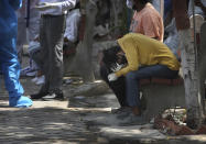 FILE In this April 19, 2021 file photo, a relative of a person who died of COVID-19 reacts during cremation, in New Delhi, India. India's health system is collapsing under the worst surge in coronavirus infections that it has seen so far. Medical oxygen is scarce. Intensive care units are full. Nearly all ventilators are in use, and the dead are piling up at crematoriums and graveyards. Such tragedies are familiar from surges in other parts of the world — but were largely unknown in India. (AP Photo/Manish Swarup, File)