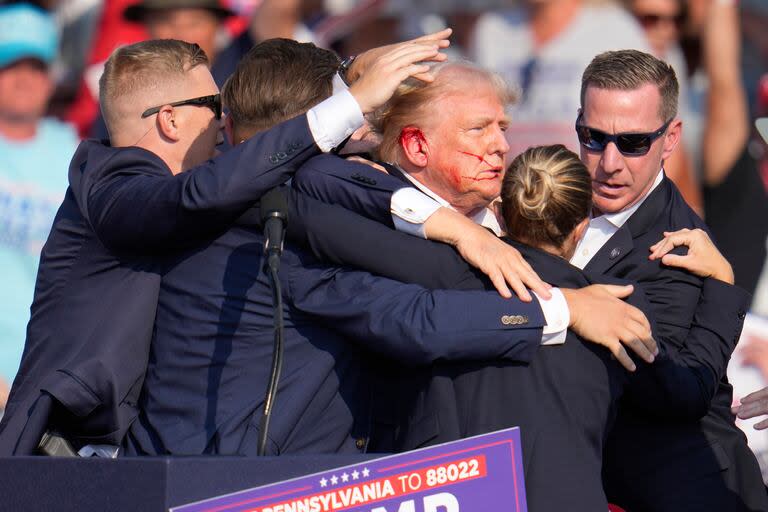 El candidato presidencial republicano, el expresidente Donald Trump, es rodeado por agentes del Servicio Secreto de Estados Unidos mientras es ayudado a bajar de la tarima en un mitin de campaña en Butler, Pensilvania, el 13 de julio de 2024. (AP/Gene J. Puskar)