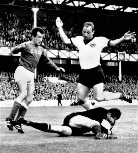 Goalkeeper Lev Yashin from the Soviet Union protects himself after recovering the ball in front of German forward Uwe Seeler 25 July 1966 in Liverpool during the World Cup semifinal match between Germany and the Soviet Union. Germany reached the final with a 2-1 victory