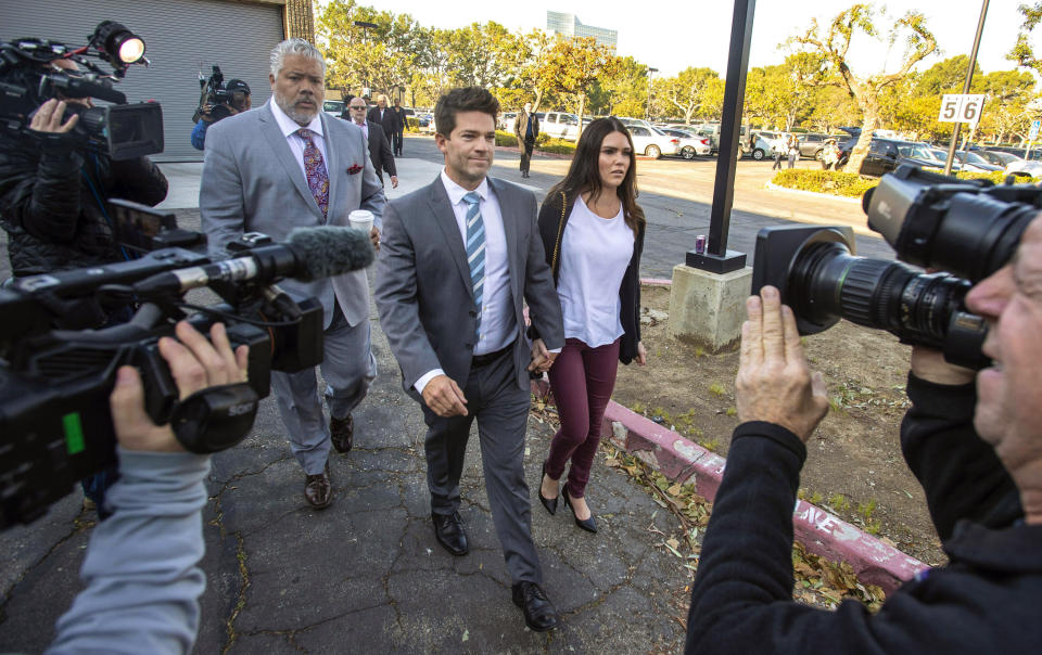 FILE - In this Friday, Feb. 7, 2020, file photo, Grant Robicheaux, center, and Cerissa Riley, arrive at Orange County Superior Court Harbor Justice Center in Newport Beach, Calif. State prosecutors want to drop most sex crime charges filed against a reality TV doctor and his girlfriend, who are accused of drugging and raping several women at their Southern California home. The attorney general's office, which took over the case last year, asked an Orange County judge on Friday, May 14, 2021, to drop charges involving six of seven alleged victims. (Mark Rightmire/The Orange County Register via AP, File)