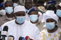 Gambian President Adama Barrow, left, speaks to journalists after casting his vote in Gambia's presidential elections, in Banjul, Gambia, Saturday, Dec. 4, 2021. Lines of voters are forming outside polling stations in Gambia’s capital as the nation holds a presidential election. The election on Saturday is the first in decades without former dictator Yahya Jammeh as a candidate. (AP Photo/Leo Correa)