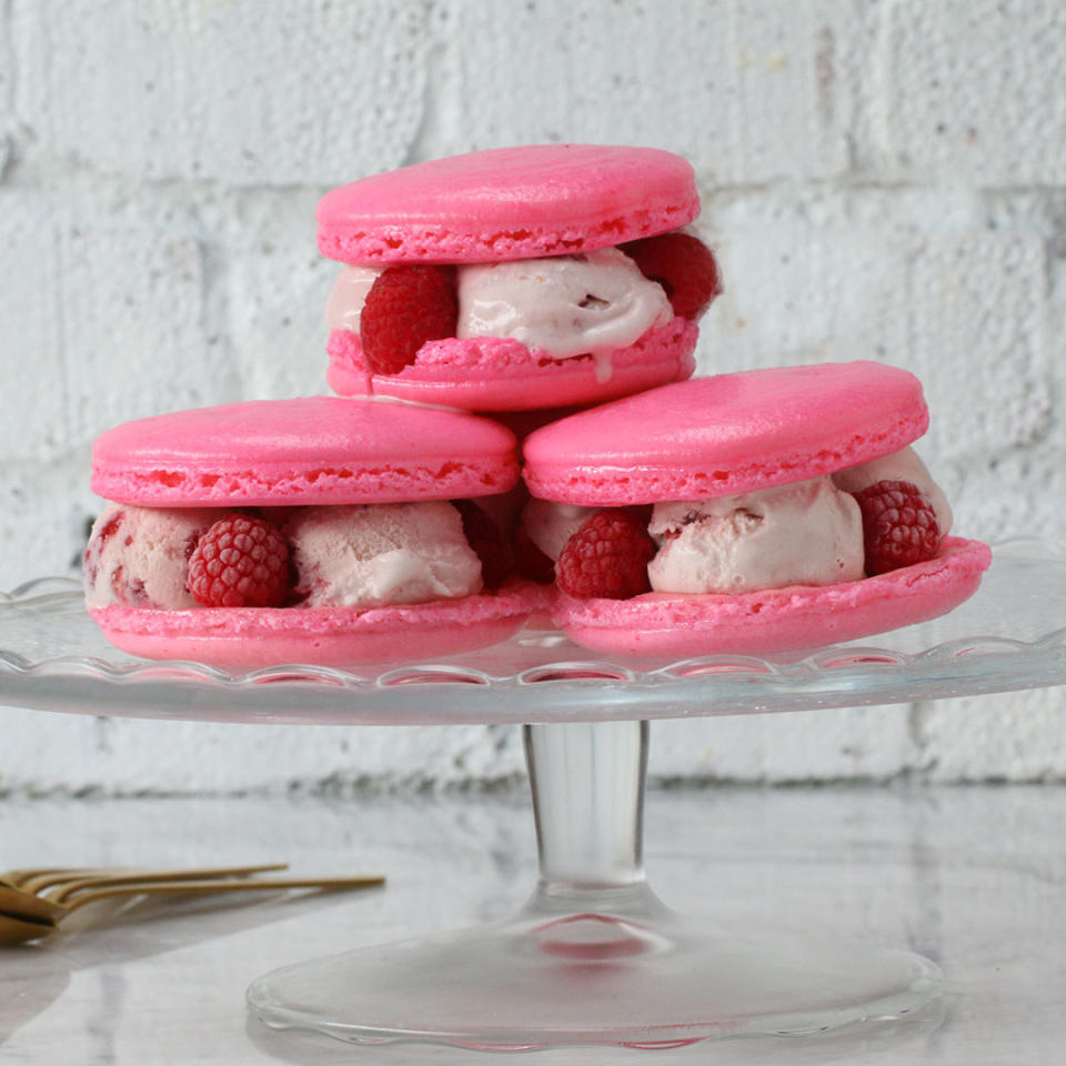 Three pink macarons filled with ice cream and berries
