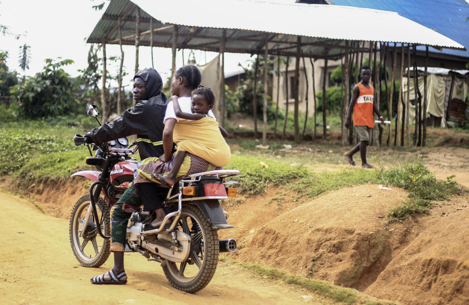 Motorcycle taxi driver Germain Kalubenge transports a woman whose 5-year-old daughter had a fever and was vomiting to an Ebola transit center where potential cases are evaluated, in Beni, Congo, Thursday, Aug. 22, 2019. Kalubenge is a rare motorcycle taxi driver who is also an Ebola survivor in eastern Congo, making him a welcome collaborator for health workers who have faced deep community mistrust during the second deadliest Ebola outbreak in history. (AP Photo/Al-hadji Kudra Maliro)