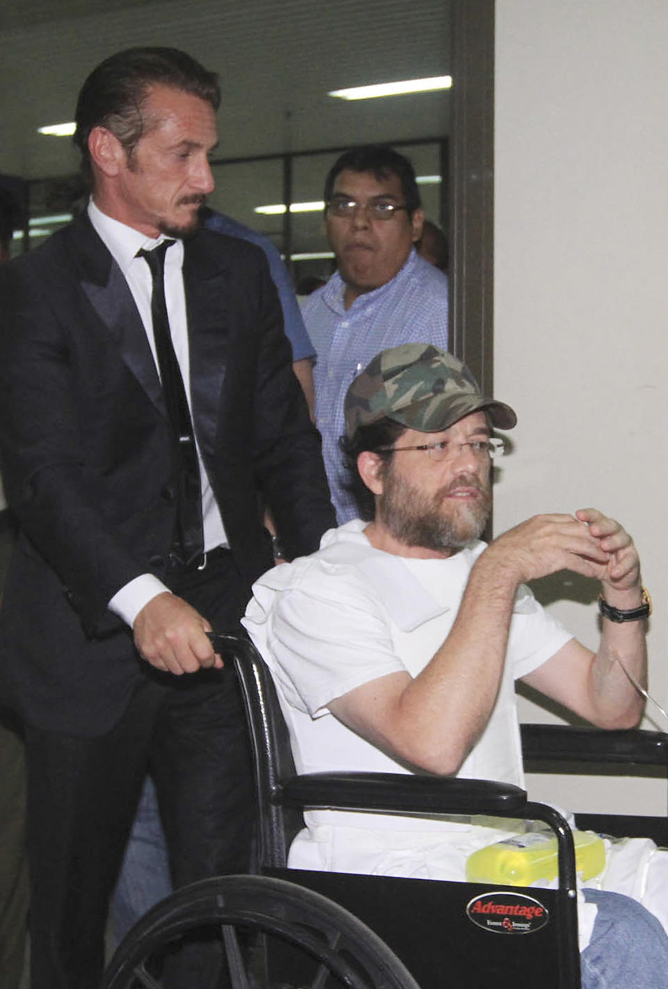 U.S. actor Sean Penn pushes U.S. businessman Jacob Ostreicher in a wheelchair, wearing a flak jacket, during a recess at Ostreicher's hearing in Santa Cruz, Bolivia, Tuesday, Dec. 11, 2012. A Bolivian appeals panel has refused to immediately release Ostreicher, despite evidence he was fleeced and extorted by prosecutors who have had him jailed for 18 months without charges on suspicion of money laundering. Ostreicher has been hospitalized for more than two weeks in a private clinic after being diagnosed with Parkinson's. Ostreicher's case led to the uncovering of a shakedown ring allegedly run by the No. 1 legal advisor in the Interior Ministry, and including two prosecutors. It came after actor Sean Pean interceded with President Evo Morales. (AP Photo)