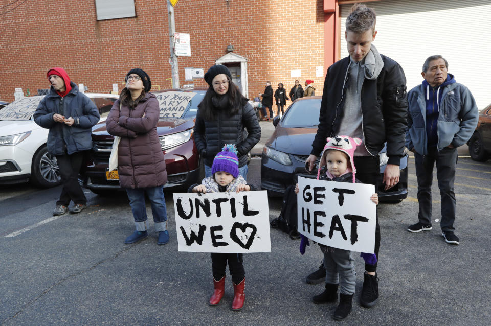 Reina Benn, 3, and her twin sister Chiara hold signs as their father, Michael Benn, second from right, keeps an eye on them as they joined other protesters and prisoners' family members at a vigil outside the Metropolitan Detention Center, a federal prison housing all security levels, Sunday, Feb. 3, 2019, in the Brooklyn borough of New York. The prison has been without heat, hot water, electricity and sanitation since an electrical failure earlier in the week. (AP Photo/Kathy Willens)