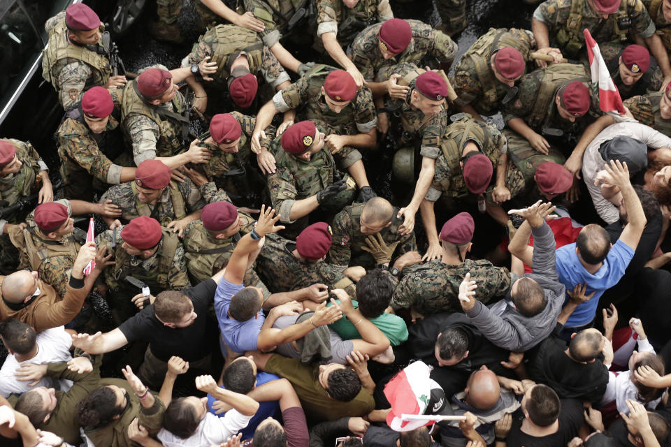 Anti-government protesters scuffle with Lebanese army soldiers during a protest in the town of Jal el-Dib north of Beirut, Lebanon, Wednesday, Oct. 23, 2019. Lebanese troops have moved in to open several major roads in Beirut and other cities, scuffling in some places with anti-government protesters who had blocked the streets for the past week. (AP Photo/Hassan Ammar)