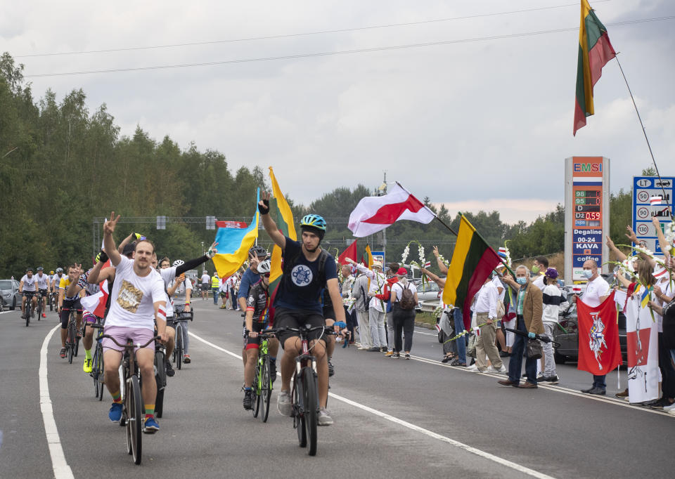 Belarusian opposition supporters ride bicycles, show victory as people create a human chain of about 50,000 strong from Vilnius to the Belarusian border during a protest near Medininkai, Lithuanian-Belarusian border crossing east of Vilnius, Lithuania, Sunday, Aug. 23, 2020. In Aug. 23, 1989, around 2 million Lithuanians, Latvians, and Estonians joined forces in a living 600 km (375 mile) long human chain Baltic Way, thus demonstrating their desire to be free. Now, Lithuania is expressing solidarity with the people of Belarus, who are fighting for freedom today. (AP Photo/Mindaugas Kulbis)