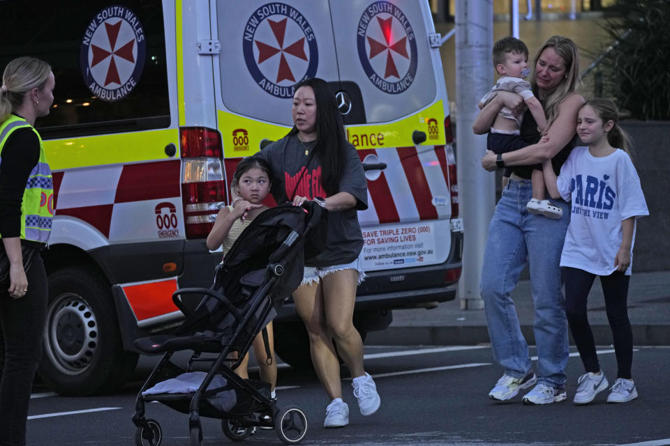 People are led out from the Westfield Shopping Centre where multiple people were stabbed in Sydney, Saturday, April 13, 2024. A man stabbed six people to death at the busy Sydney shopping center Saturday before he was fatally shot, police said. Multiple people, including a small child, were also injured in the attack. (AP Photo/Rick Rycroft)