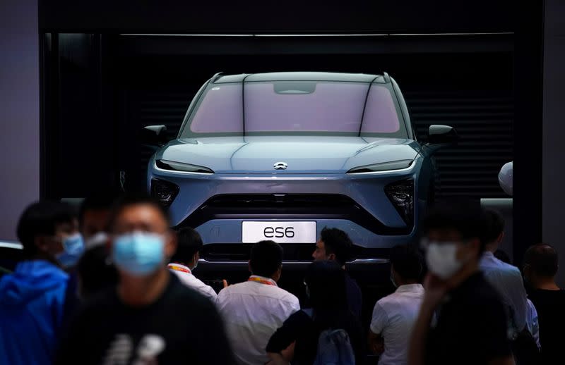 FILE PHOTO: People wearing face masks look at a Nio ES6 EV car at the Beijing International Automotive Exhibition