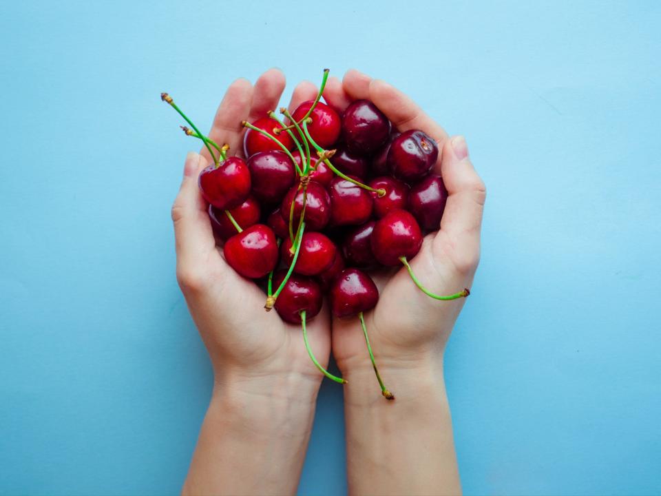 cherry in hand on a blue background
