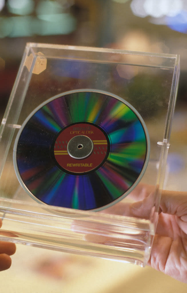 A rewritable CD in a clear plastic case being held in a person's hands