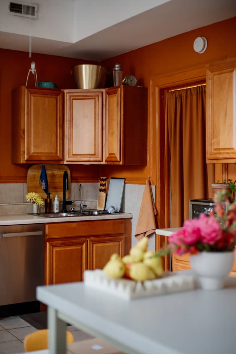 Rust painted wall in kitchen with wooden cabinets.