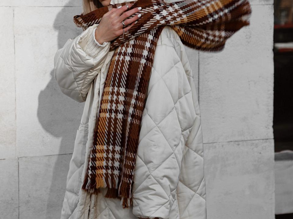 woman wearing quilted jacket and a plaid scarf and an orange hat