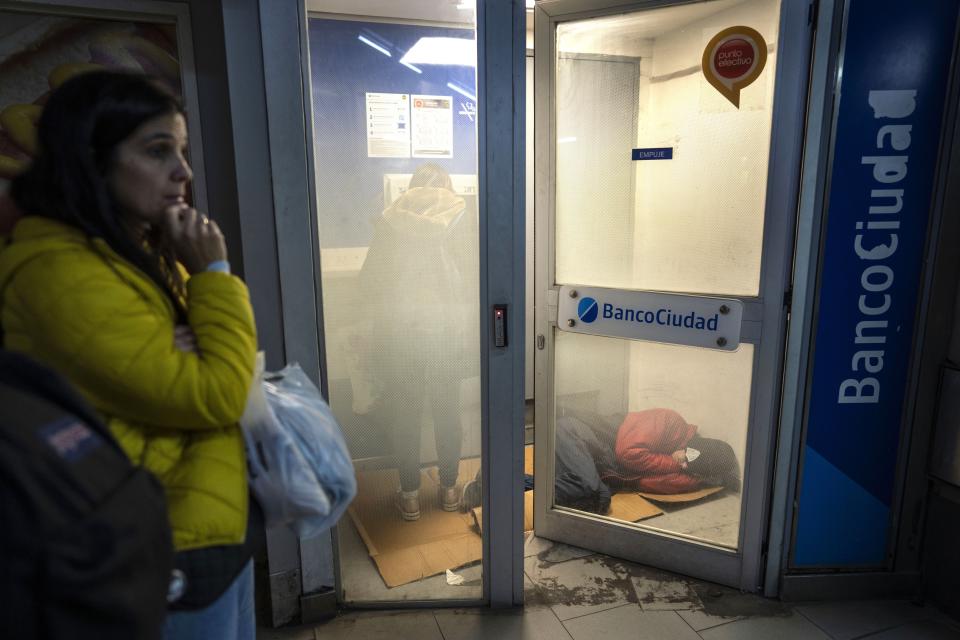 Una persona duerme dentro del área de cajeros automáticos de un banco en Buenos Aires, Argentina, el lunes 24 de junio de 2024. (AP Foto/Rodrigo Abd)