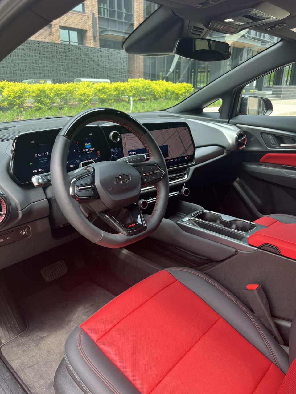 interior photo of 2024 chevy equinox ev showing the drivers seat steering wheel and digital screens with red inserts in the seats