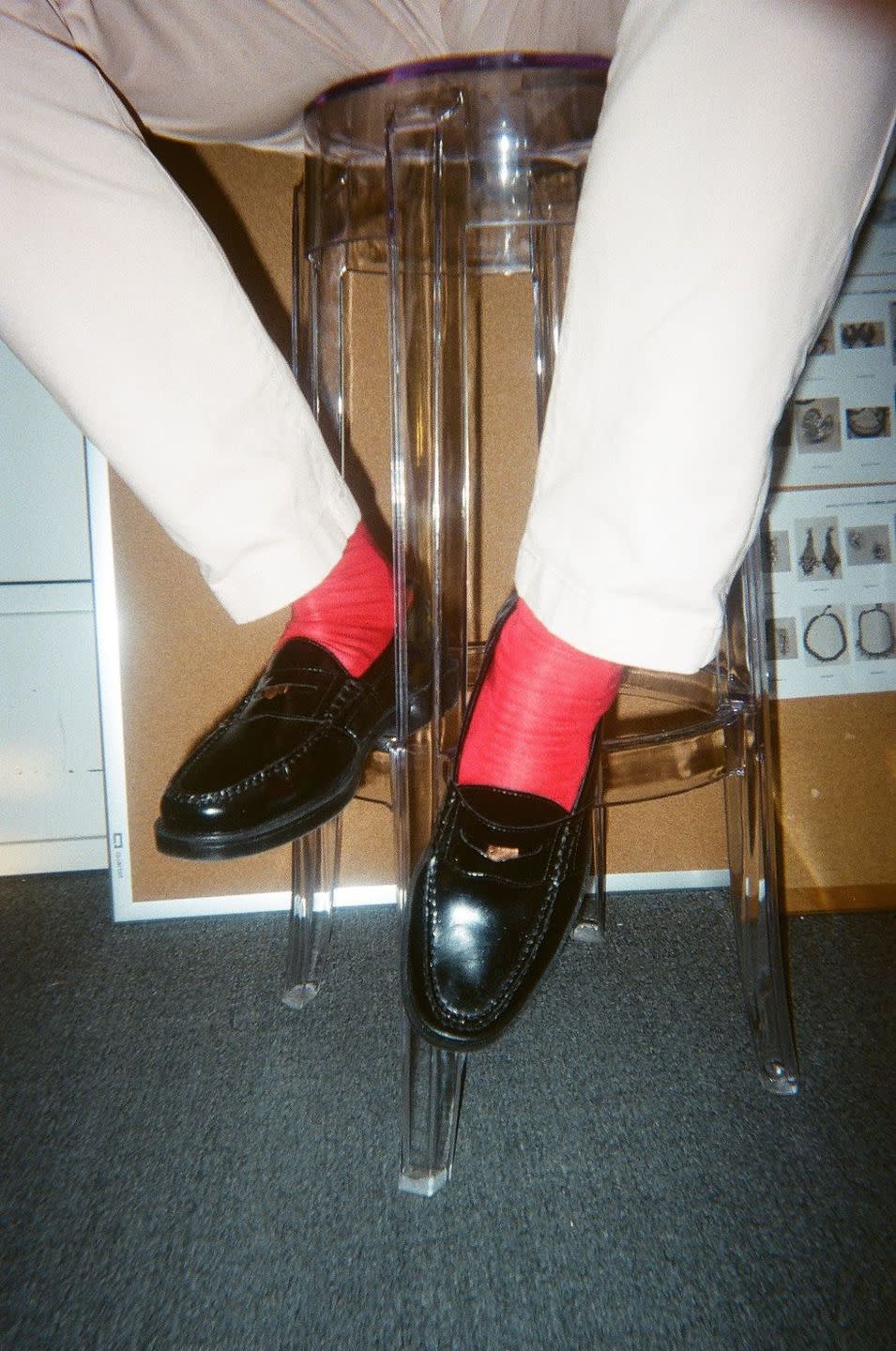 a person wearing loafers and red socks sitting on a stool