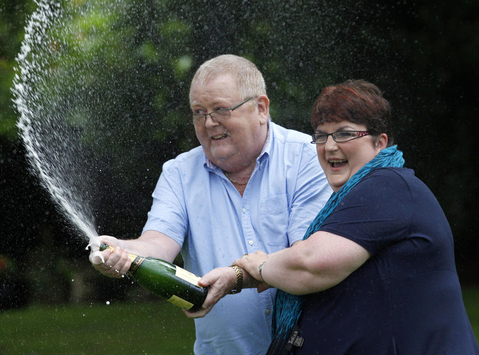 Colin Weir (L) and his wife Chris spray a bottle of champagne after a news conference at a hotel near Falkirk, Scotland July 15, 2011. The couple scooped 161 million pounds ($259 million) in Tuesday's Euromillions jackpot.   REUTERS/David Moir (BRITAIN - Tags: SOCIETY)