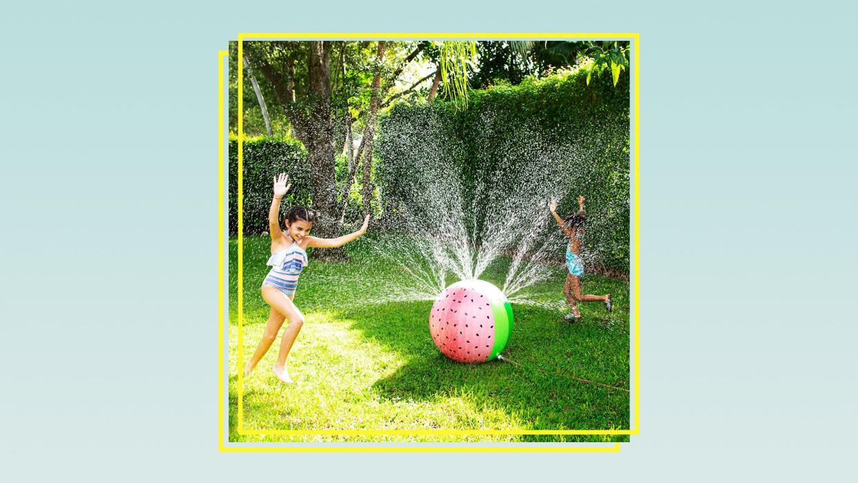two kids playing in a sprinkler shaped like a watermelon